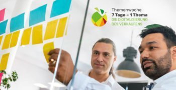 Zwei Mitarbeiter kleben Post-its gegen ein Glaswand