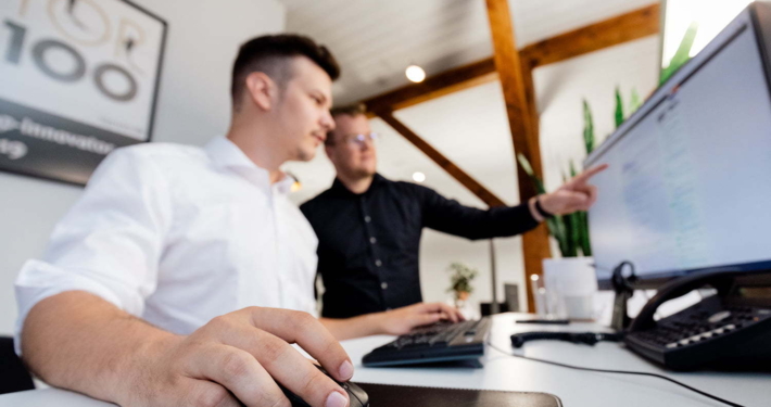 Zwei Mitarbeiter arbeiten zusammen an einem Computer in der Magento-Agentur