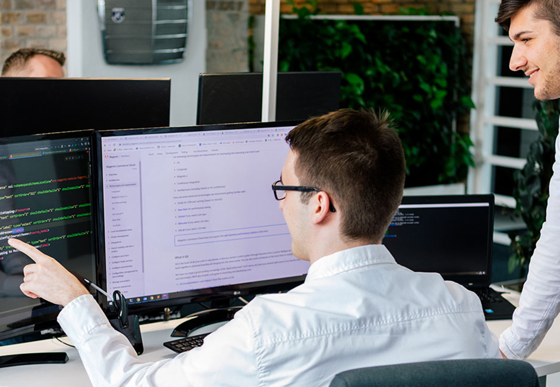 Zwei Männer schauen auf einen Computerbildschirm und scheinen sich über den Inhalt auszutauschen.