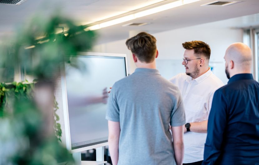 Drei Teammitglieder einer WordPress-Agentur stehen vor einem interaktiven Whiteboard und planen gemeinsam ein Webprojekt – agile Zusammenarbeit für maßgeschneiderte WordPress-Lösungen.