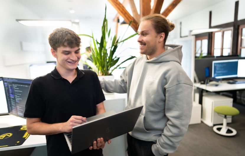 Shopware-schnittstellen-support Person hält ein Notebook in der Hand, im Hintergrund ein modernes Büro.