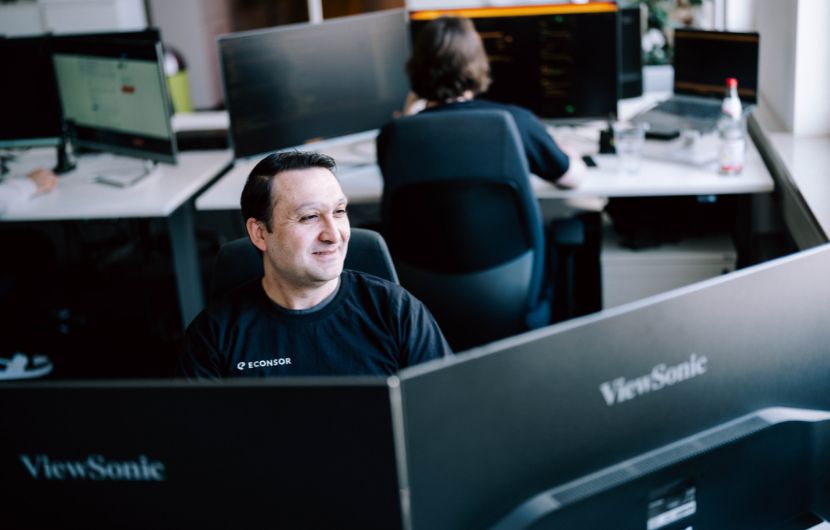 Shopware-schnittstellen IT-Arbeitsplatz in einem modernen Büro mit mehreren Monitoren und Mitarbeitenden