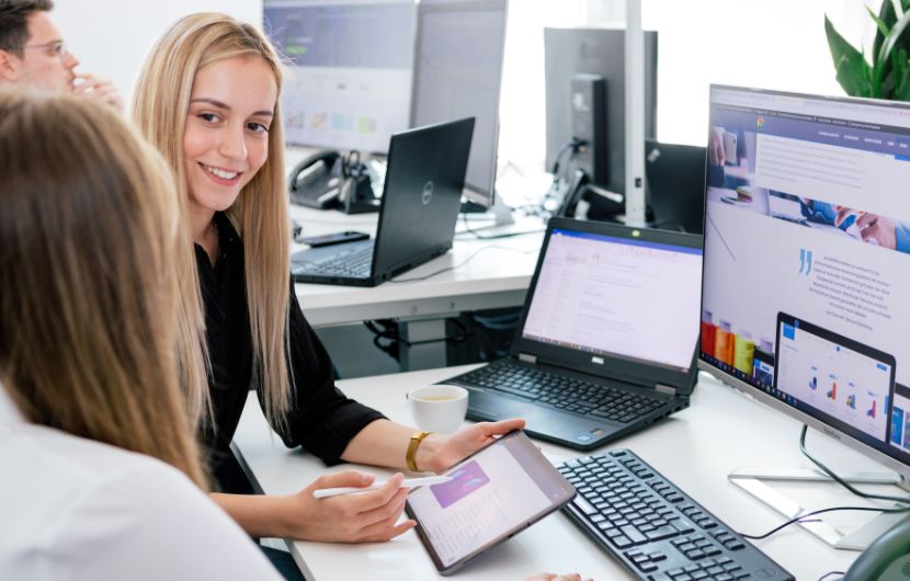 In einem großzügigen Büro planen Mitarbeiter einer Performance-Marketing-Agentur digitale Kampagnen und analysieren detaillierte Kennzahlen – die Szene vermittelt eine professionelle und innovative Agentur für Performance-Marketing.