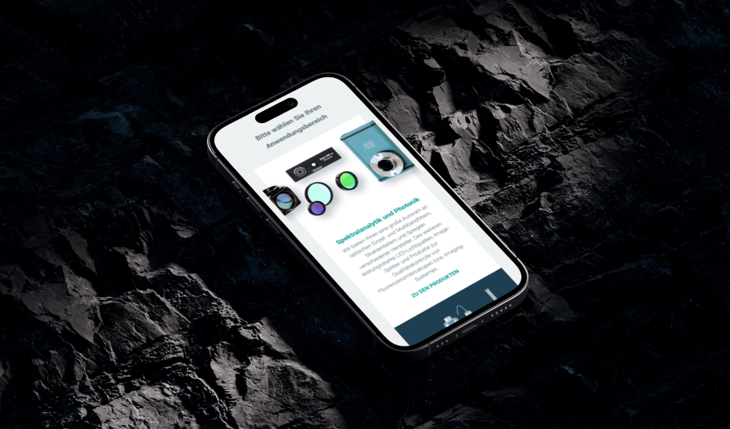 Ein Smartphone liegt flach auf einer dunklen, steinigen Oberfläche. Auf dem Bildschirm des Smartphones ist der AHF-Shop abgebildet. 