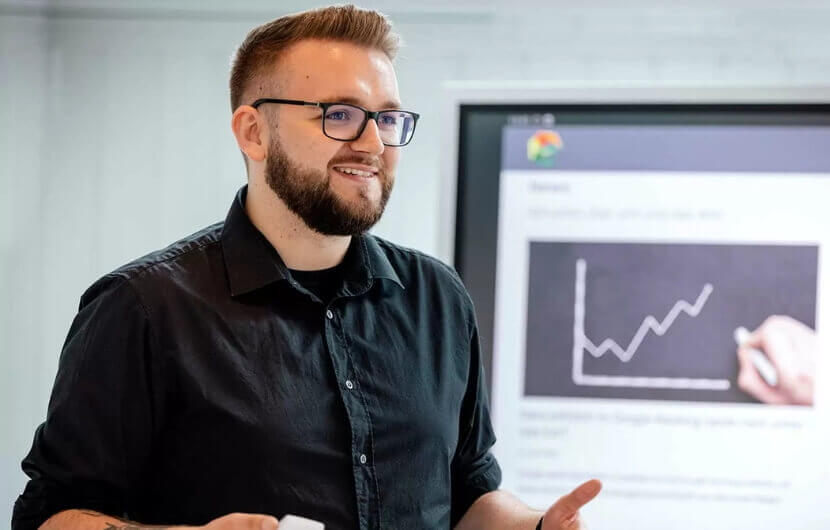 Kollege steht am Smartboard und schult einen Kunden