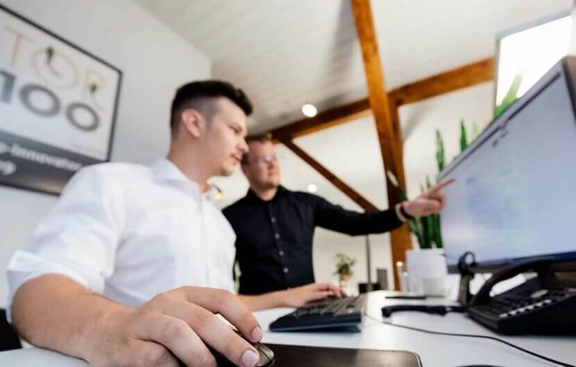 Zwei Kollegen sitzen an einem Bildschirm und optimieren die Conversion-Rate eines B2B-Kunden