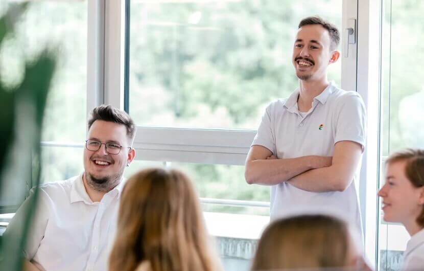 Ein Bild verschiedener Mitarbeiter die im Büro stehen und sich besprechen