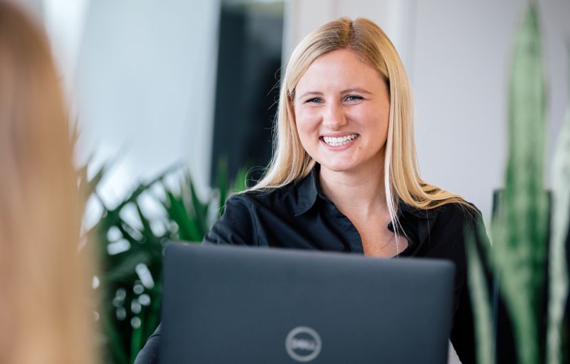 Marketing-Automation durch erfahrene Experten Eine lächelnde Expertin für Marketing-Automation arbeitet an einem Laptop und berät Kunden in einem hellen, begrünten Büro – repräsentiert die professionelle Expertise in Automationsprojekten.
