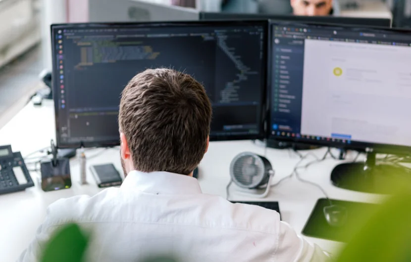 Motivierter Mitarbeiter Ein Mitarbeiter sitzt an seinem Arbeitsplatz und analysiert einen Code.