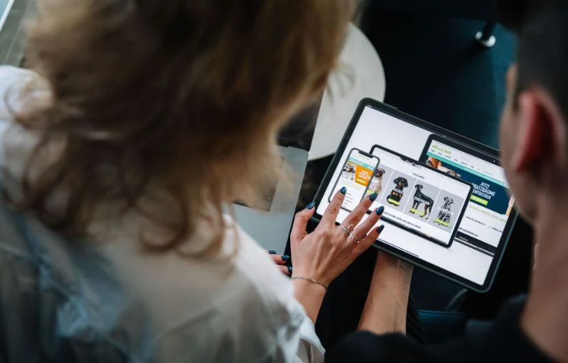 Zwei Mitarbeiter schauen sich auf einem Tablet eine Kundenpräsentation an.