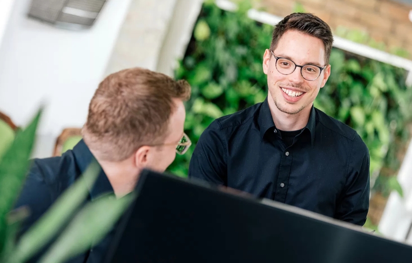 Zwei Online-Marketing-Profis besprechen sich vor einem Computer