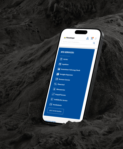 Ein Smartphone steht hochkant auf einem düsteren und unebenem Stein. Auf dem Bildschirm des Smartphones ist der Pneuhage-Shop abgebildet.