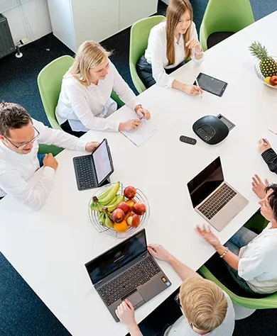 Team der WordPress-Agentur bei einer Besprechung mit Laptops und frischem Obst am Konferenztisch