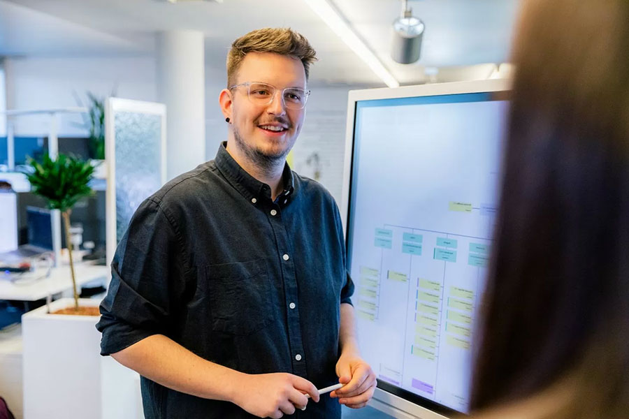 Ein Mitarbeiter einer Internetagentur präsentiert eine digitale Struktur auf einem großen Monitor – wir sind Ihr Partner für die Umsetzung Ihrer barrierefreien Webseite und entwickeln inklusive Weblösungen.