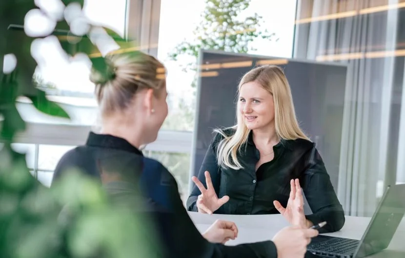 Zwei Mitarbeiterinnen besprechen strategische Webthemen in einem hellen Besprechungsraum – Fokus auf individuelle digitale Beratung.