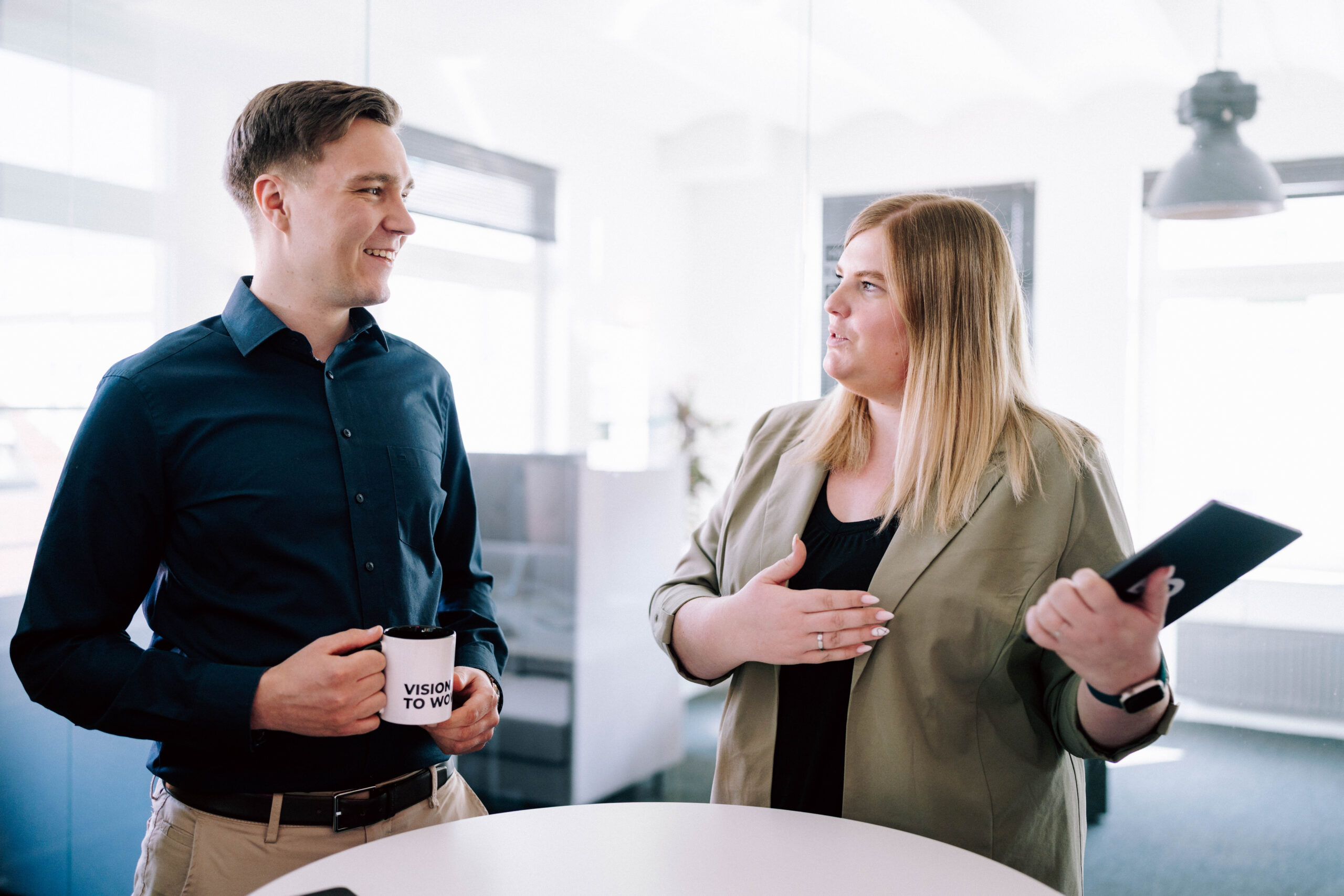 Zwei ECONSOR-Mitarbeiter stehen um einen Tisch und besprechen ein Kundenprojekt – die Szene illustriert dynamische Teamarbeit in einer modernen Online-Marketing-Agentur.