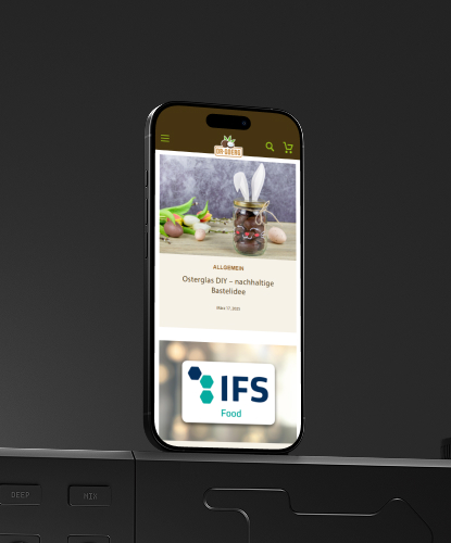 Ein Smartphone steht hochkant auf einer düsteren Oberfläche. Auf dem Bildschirm des Smartphones ist der Dr.Goerg-Shop abgebildet.