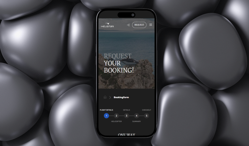 Ein Smartphone liegt flach auf einer dunklen, steinigen Oberfläche. Auf dem Bildschirm des Smartphones ist die HELISTAR-Website abgebildet.