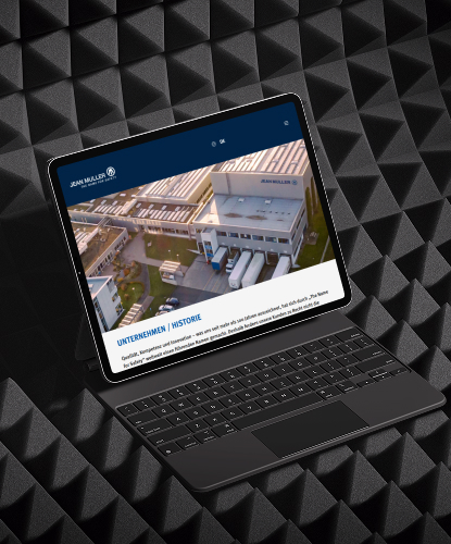 Ein Tablet steht quer auf einem dunkelen Untergrund. Auf dem Bildschirm des Tablets ist die Jean Müller-Website abgebildet.