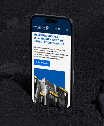 Ein Smartphone steht hochkant auf einem düsteren Untergrund. Auf dem Bildschirm des Smartphones ist die Jean Müller-Website abgebildet.