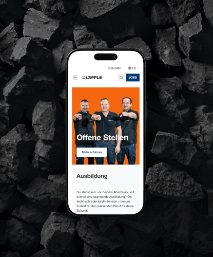 Ein Smartphone liegt flach auf einer dunklen, steinigen Oberfläche. Auf dem Bildschirm des Smartphones ist die LÄPPLE-Website abgebildet.
 