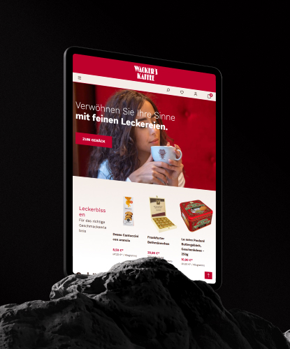 Ein Tablet steht hochkant auf einem düsteren und unebenem Stein. Auf dem Bildschirm des Tablets ist der Wacker's-Shop abgebildet.