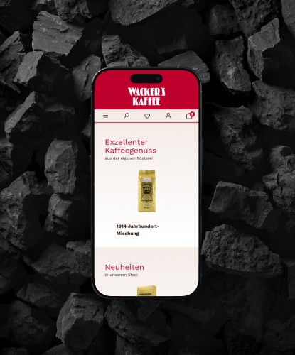 Ein Smartphone liegt flach auf einer dunklen, steinigen Oberfläche. Auf dem Bildschirm des Smartphones ist der Wacker's-Shop abgebildet.