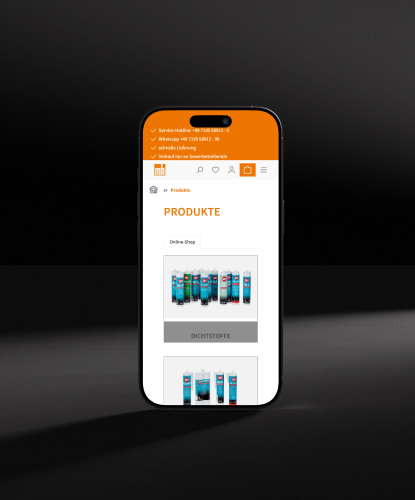 Häussler Dichtstoffe Referenz Mockup Mobil Ein Smartphone steht hochkant auf einem düsteren und unebenem Stein. Auf dem Bildschirm des Smartphones ist der Häussler Dichtstoffe-Shop abgebildet.