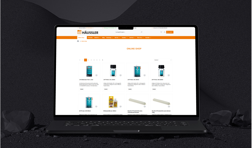 Häussler Dichtstoffe Referenz Mockup Laptop Ein Laptop steht auf einer düsteren Oberfläche. Auf dem Bildschirm des Laptops ist die Häussler Dichtstoffe-Website abgebildet.