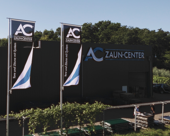 Firmengebäude des AC Zaun-Center mit Firmenlogo und zwei Werbefahnen