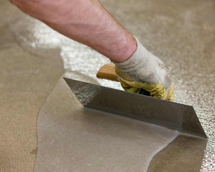 Hand verteilt mit einer Kelle frischen Bodenbelag