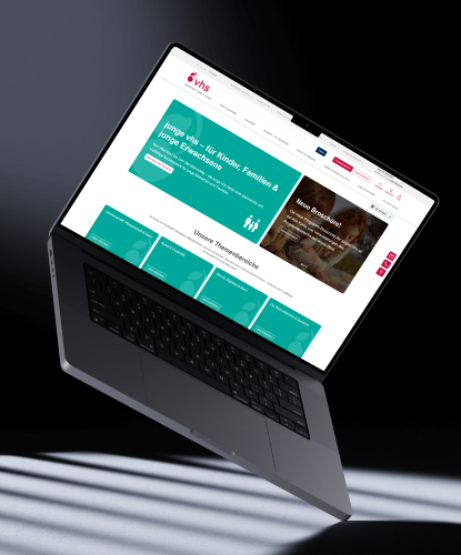 Ein Laptop schwebt über eine Fläche. Darauf abgebildet ist die Website der vhs Stuttgart