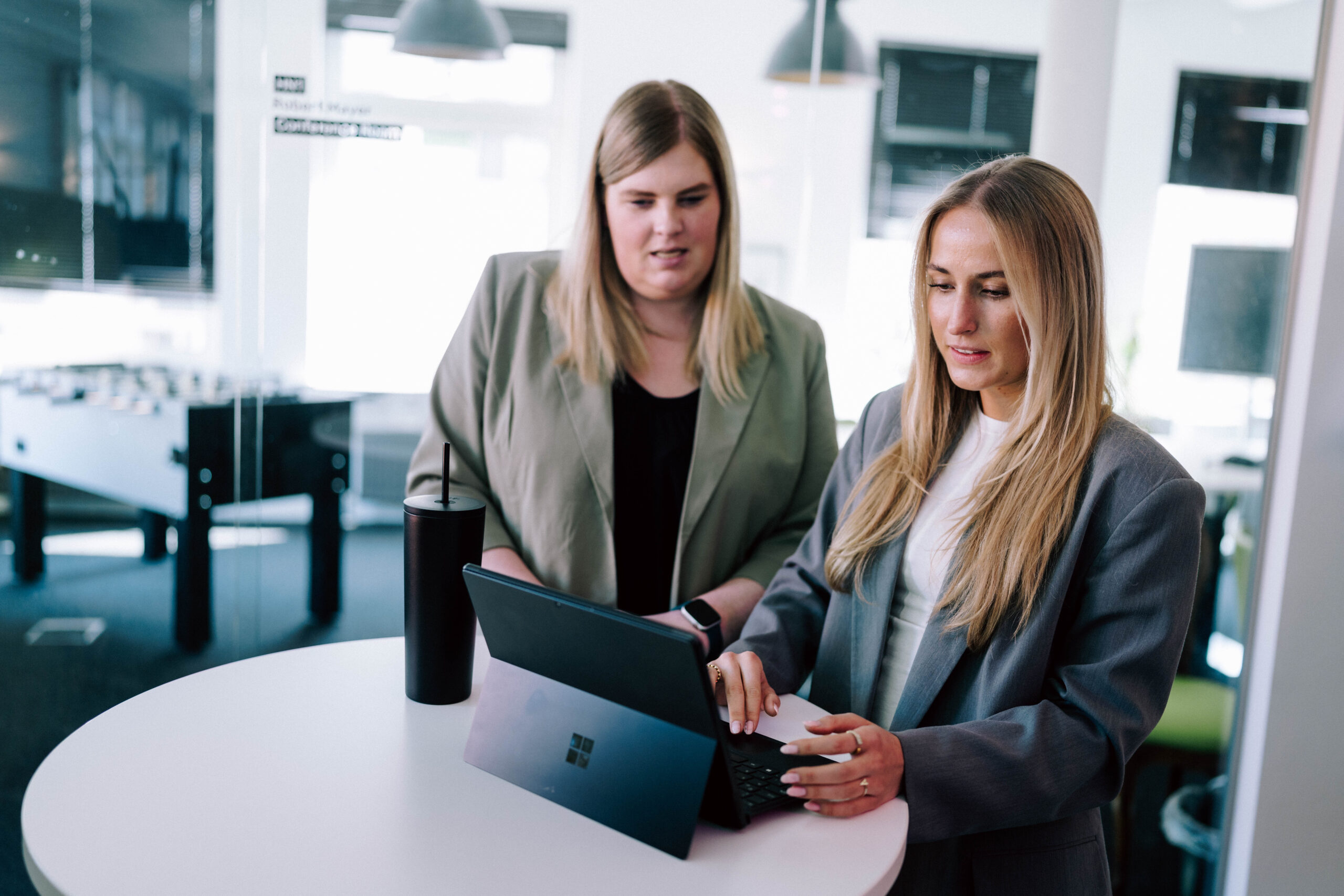 Was kostet Nichtstun? Der wahre Preis eines veralteten Systems Zwei Frauen stehen zusammen an einem Laptop.