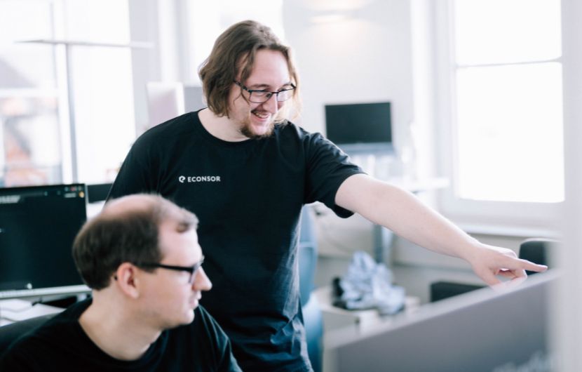 magento_Testing Zwei Softwareentwickler arbeiten gemeinsam am Computer im Büro und besprechen Code