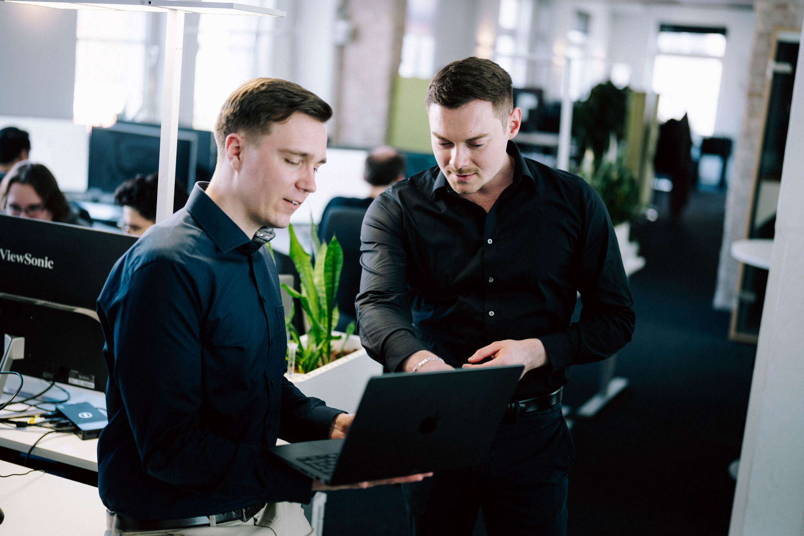 Zwei ECONSOR-Mitarbeiter besprechen gemeinsam Inhalte an einem Laptop im modernen Büro der Digitalagentur.