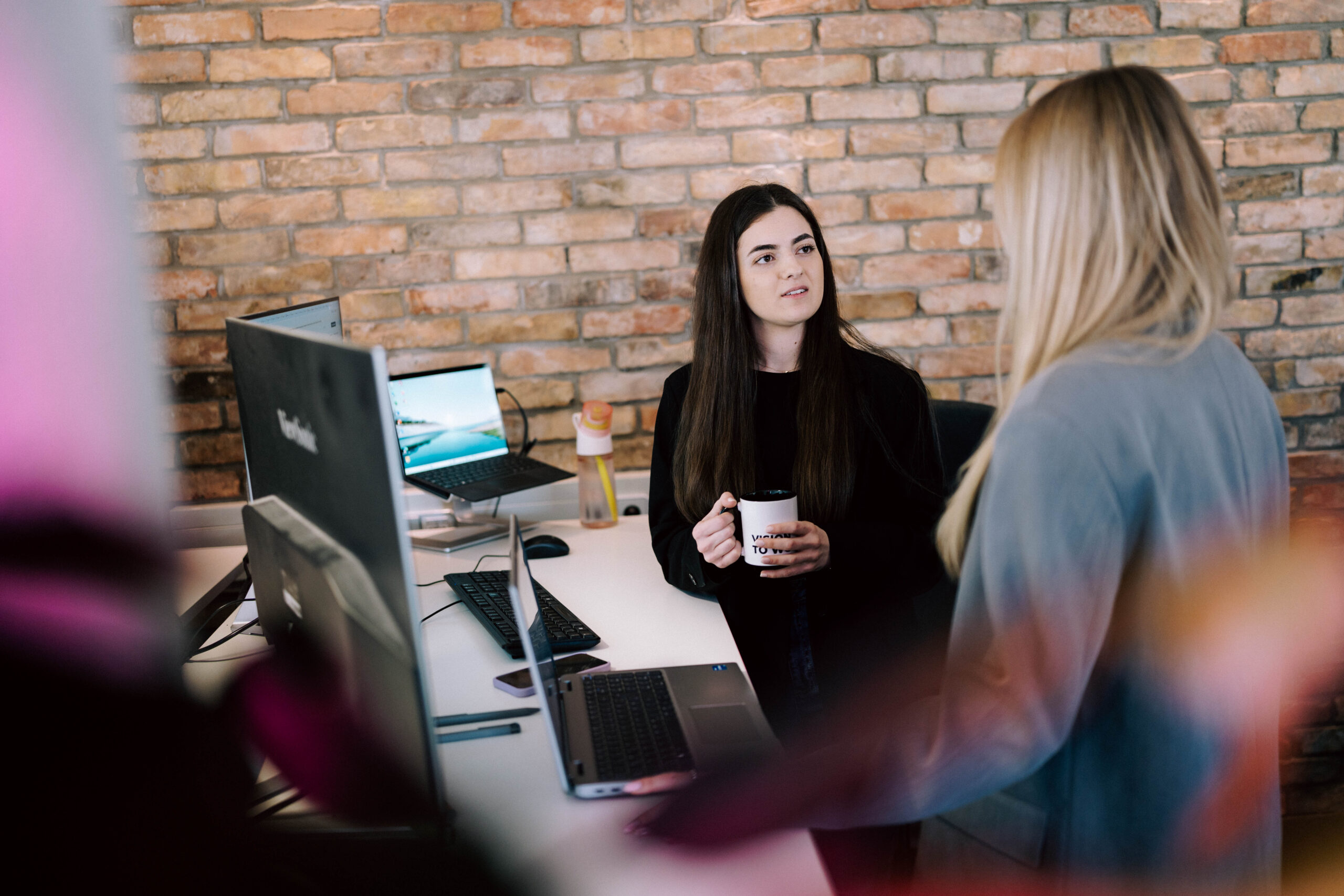 Online-Marketing-Agentur in Wien Zwei Mitarbeiterinnen im Gespräch am Arbeitsplatz