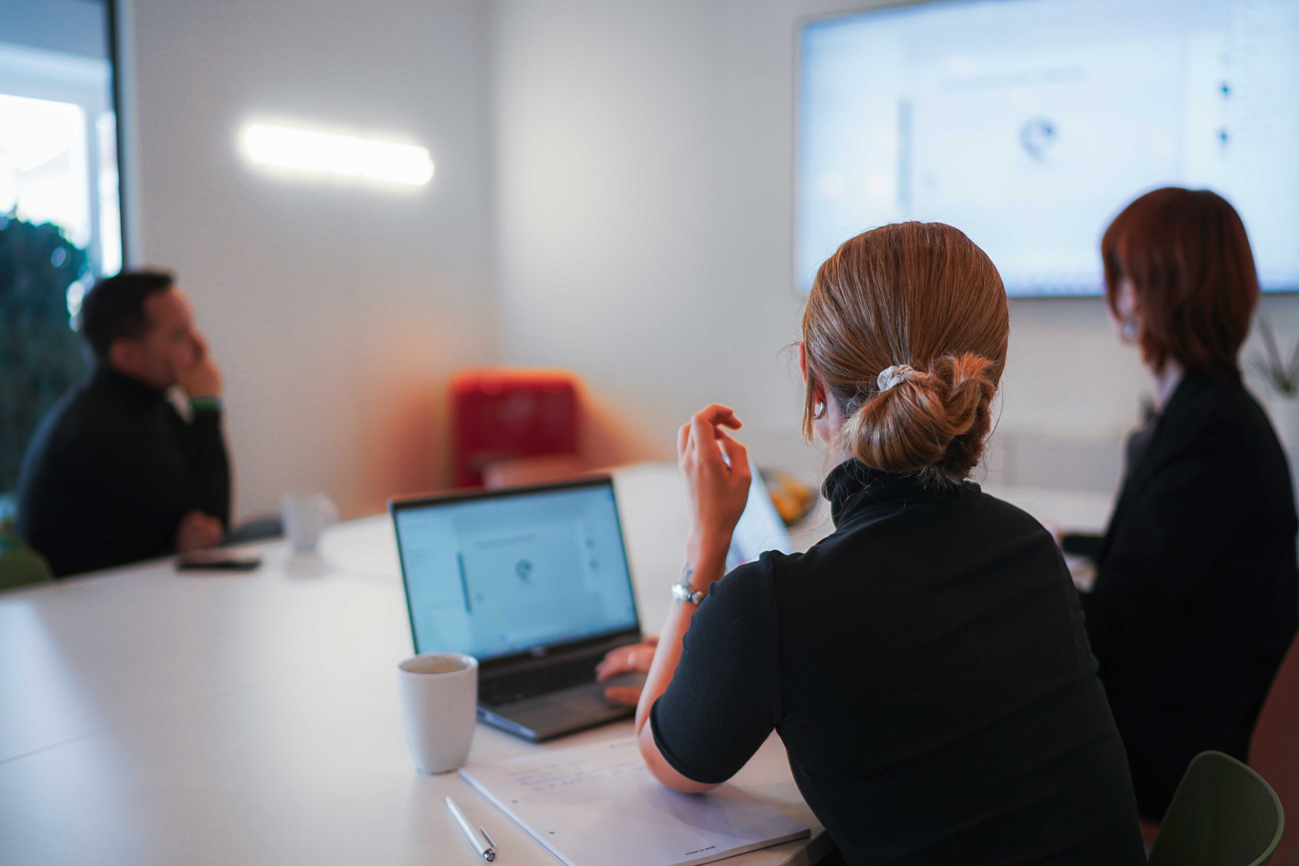 Digital First Branding Drei Personen besprechen in einem Meeting digitale Markenführung und Nutzererlebnisse, während eine Präsentation auf einem Bildschirm gezeigt wird.