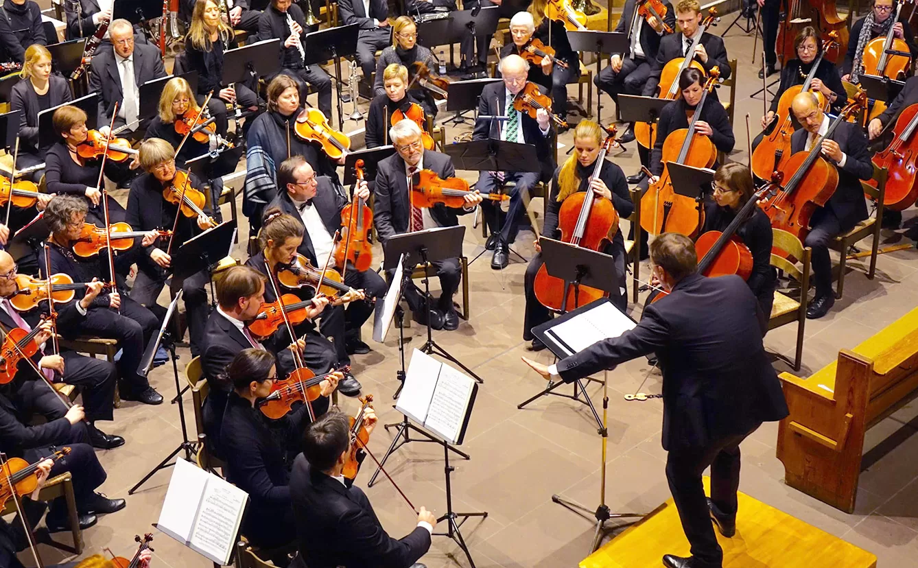 Daimler Musikgemeinschaft Orchester mit vielen Violinen und Cellos und einem Dirigenten