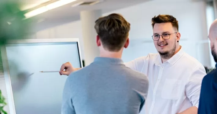 Mitarbeiter beraten sich vor einem Whiteboard