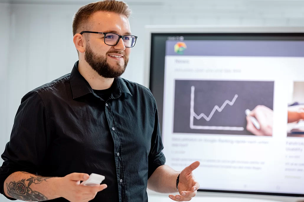 Mann steht vor einem digitalen Whiteboard und erklärt etwas