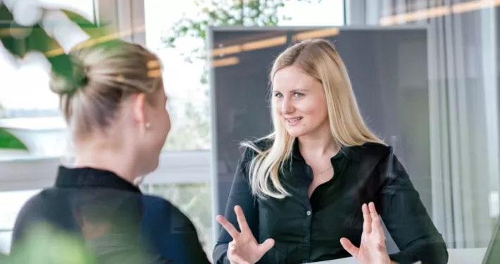 Zwei Menschen sitzen an einem Besprechungstisch im Büro