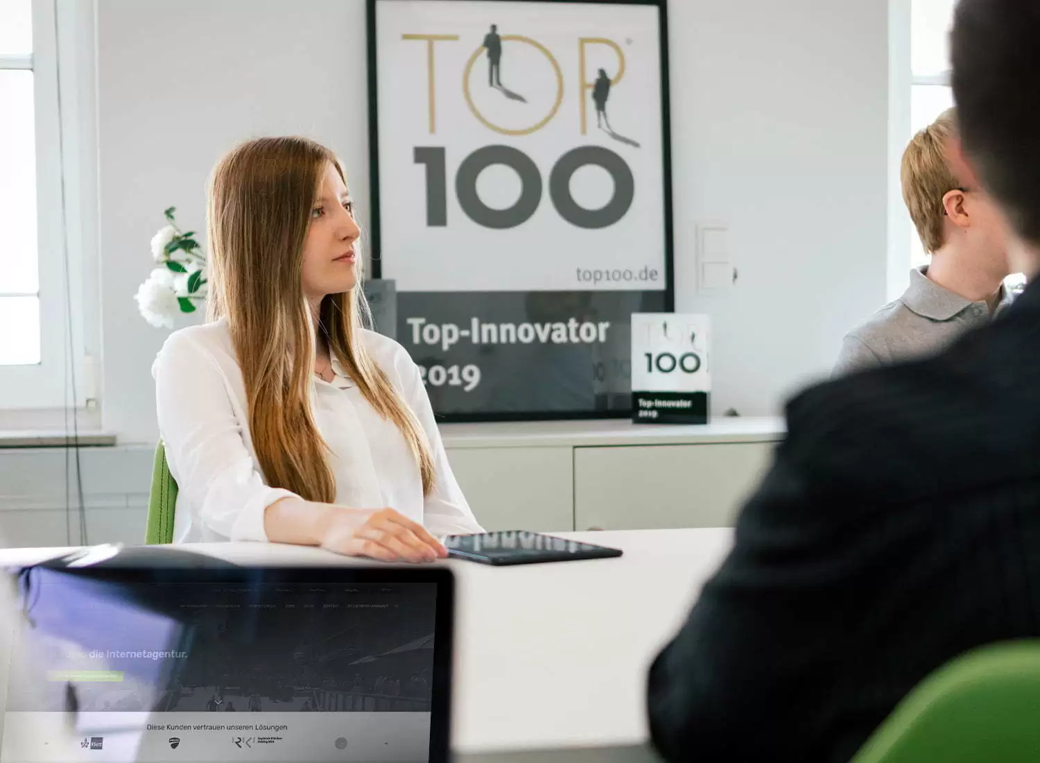Mitarbeiterin in einem Meeting zum Thema Online-Marketing-Beratung, im Hintergrund ein Top-Innovator-Award