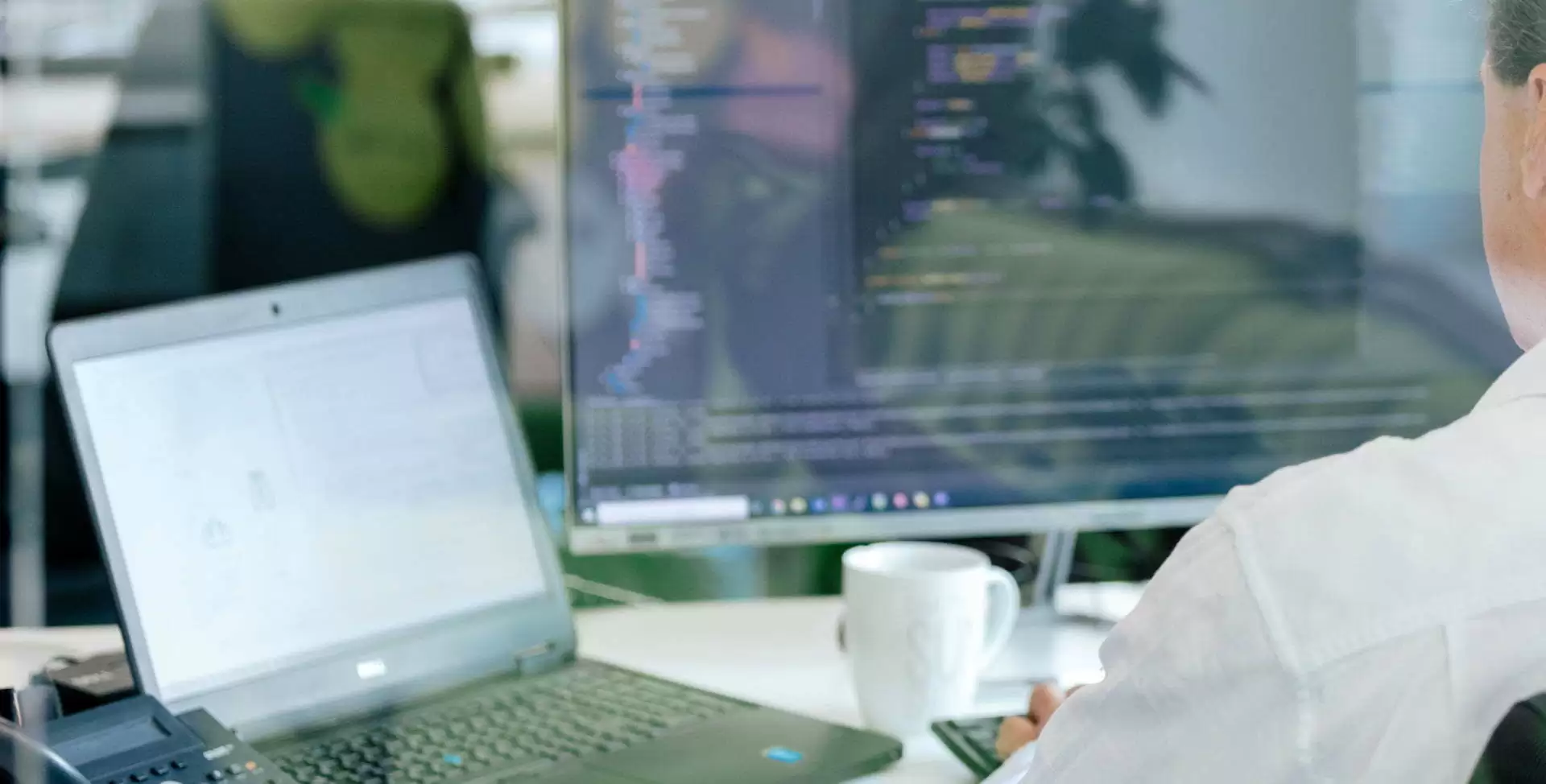 Entwickler sitzt am Computer und bearbeitet Quellcode