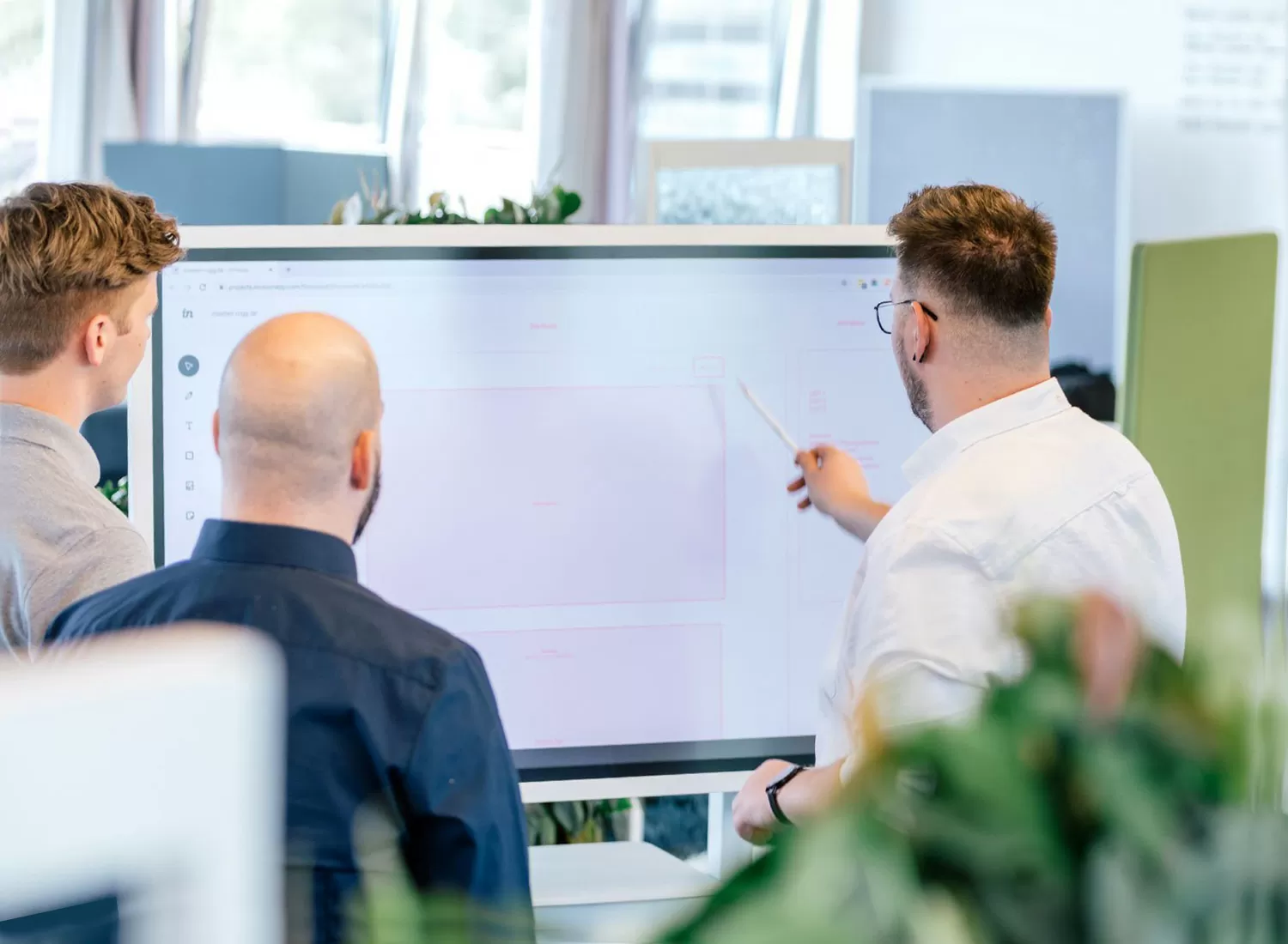 Mitarbeiter stehen vor einem digitalen Whitebaord und besprechen ein Webdesign