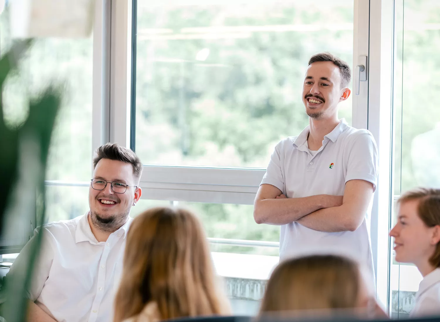 Ein Bild verschiedener Mitarbeiter die im Büro stehen und sich besprechen