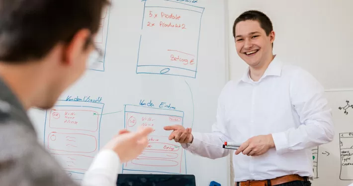 Mitarbeiter vor einem Whiteboard - Besprechung