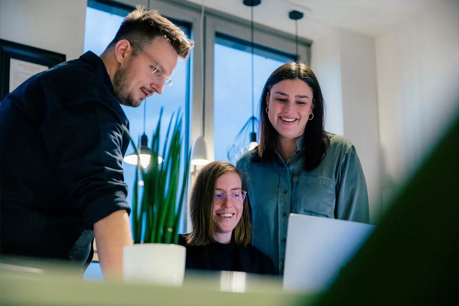 Drei Mitarbeiter halten eine Besprechung vor einem Laptop