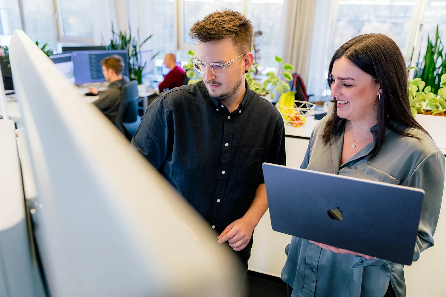 Drei Mitarbeiter besprechen zusammen etwas an einem Computer