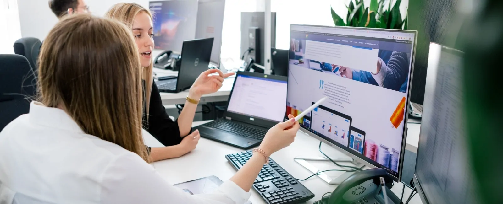 Zwei Mitarbeiter betrachten ein Webdesign auf einem Rechner