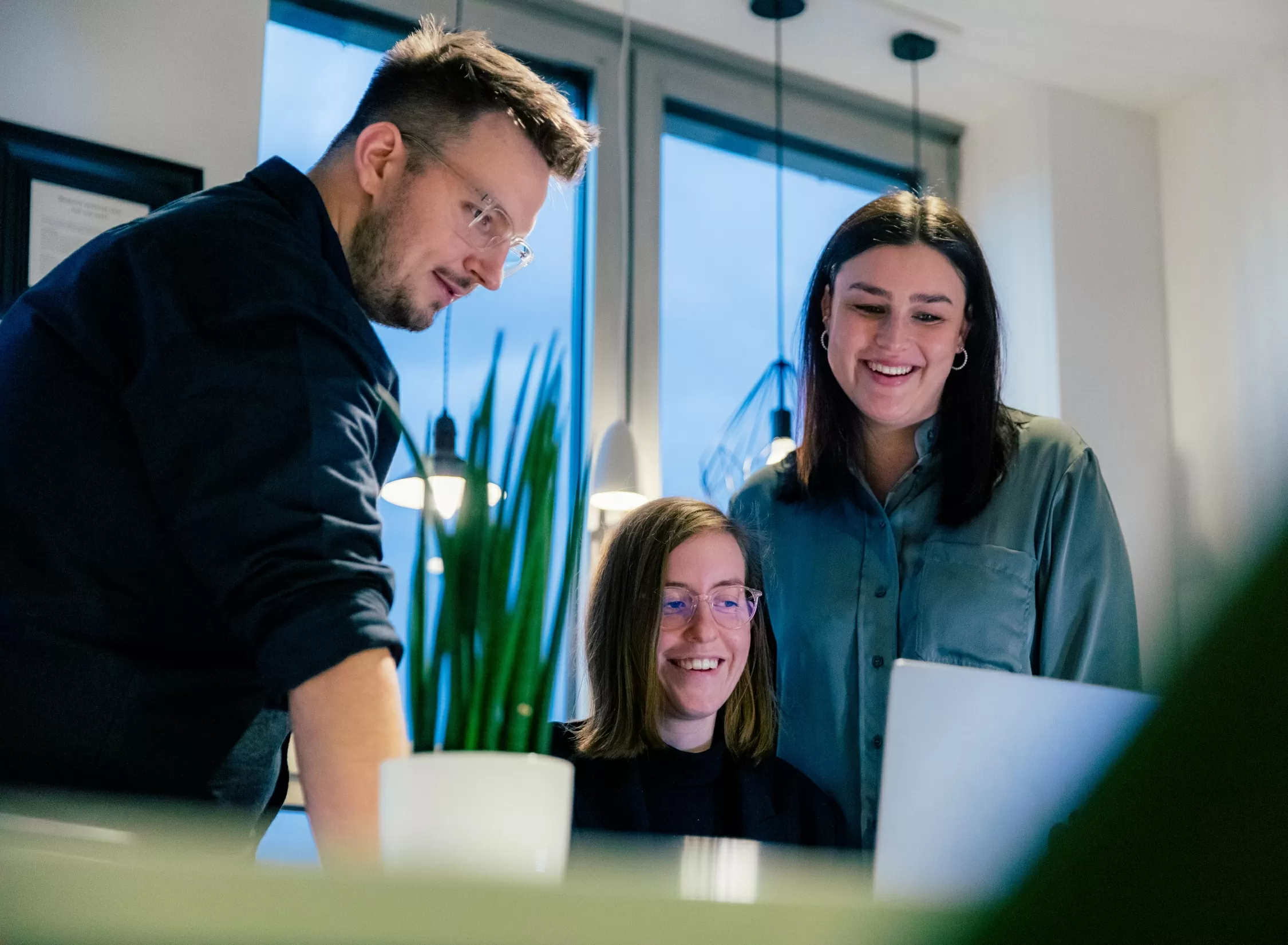 Drei Mitarbeiter halten eine Besprechung vor einem Laptop